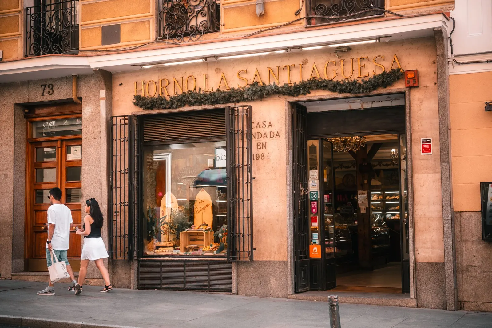 Fachada de un horno tradicional en una calle de Madrid con peatones pasando por delante