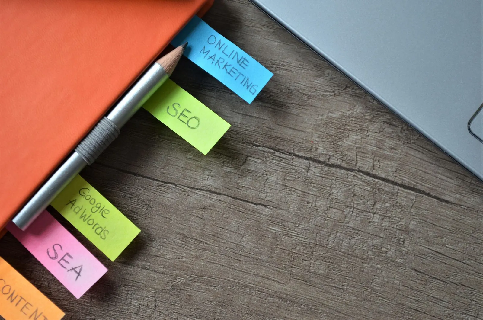 Notas adhesivas de colores con las palabras SEO y marketing online sobre una libreta y una mesa de madera
