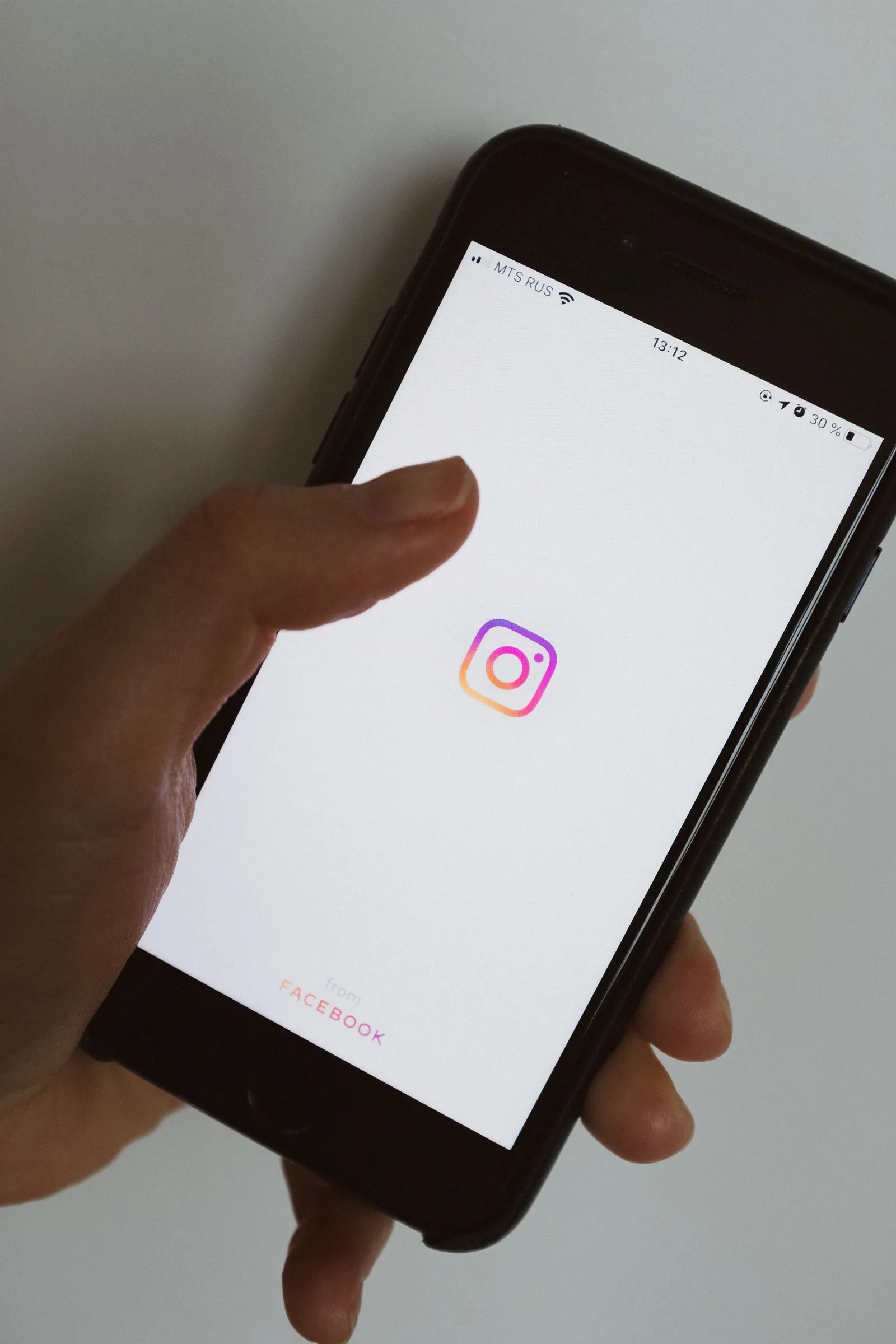 Mano sosteniendo un teléfono móvil con el logotipo de una red social en la pantalla
